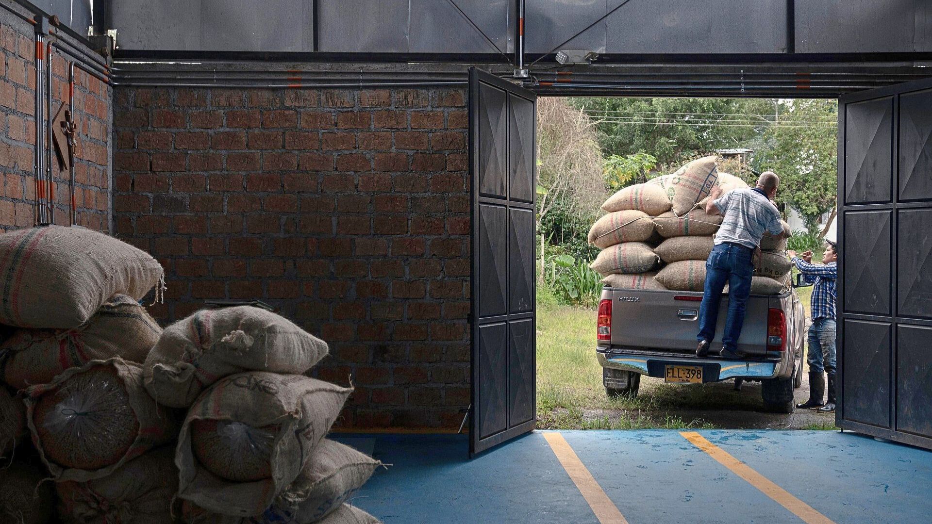 Green coffee bags from multiple origins being unloaded during intake, highlighting lot management and consistency challenges for roasteries