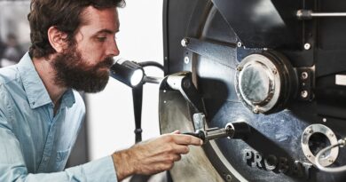 Coffee roaster inspecting roast development while heat distribution inside a coffee bean illustrates heat transfer during coffee roasting