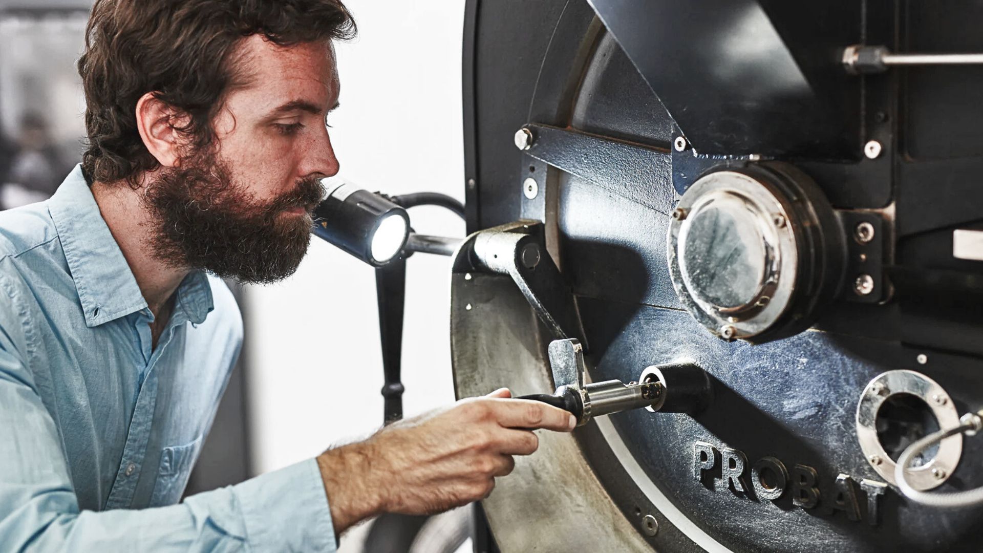 Coffee roaster inspecting roast development while heat distribution inside a coffee bean illustrates heat transfer during coffee roasting