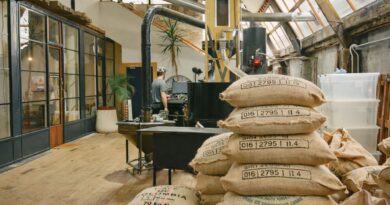 Green coffee sacks inside a roastery highlighting smart coffee sourcing, production stability, and flavor consistency