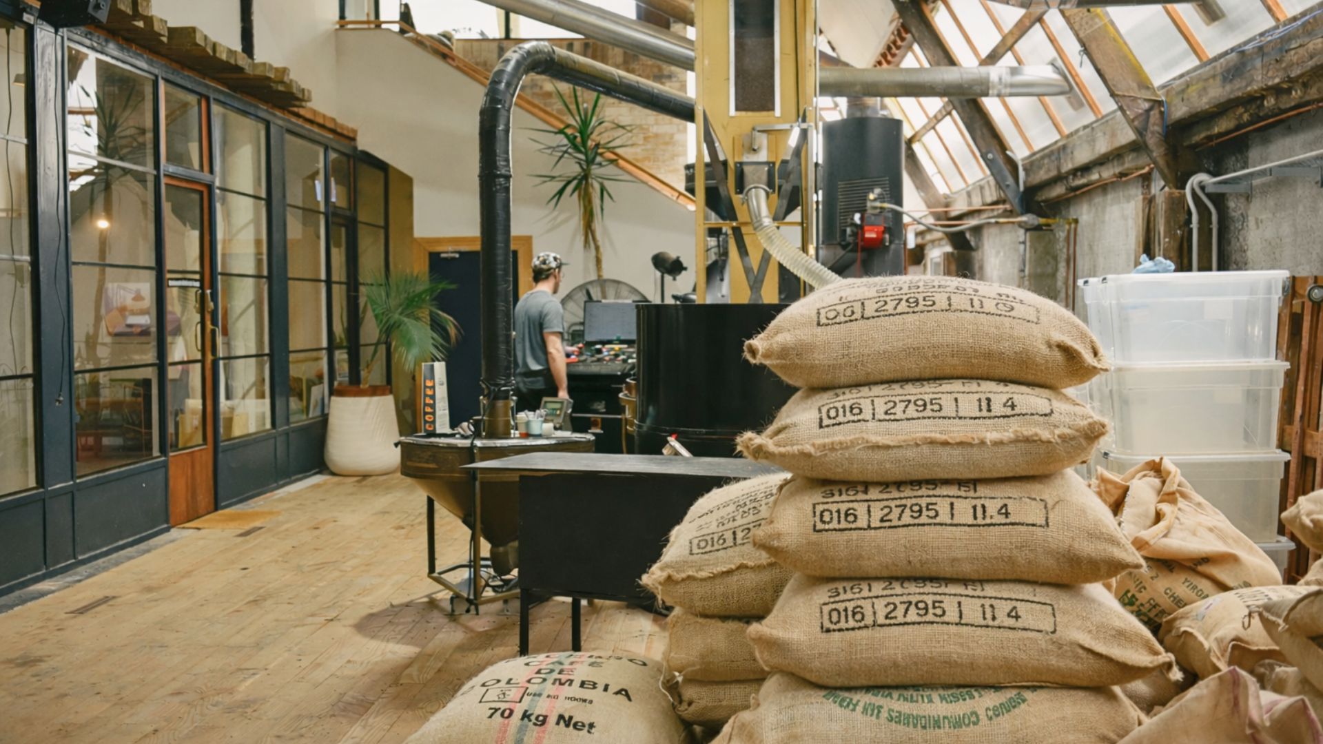 Green coffee sacks inside a roastery highlighting smart coffee sourcing, production stability, and flavor consistency