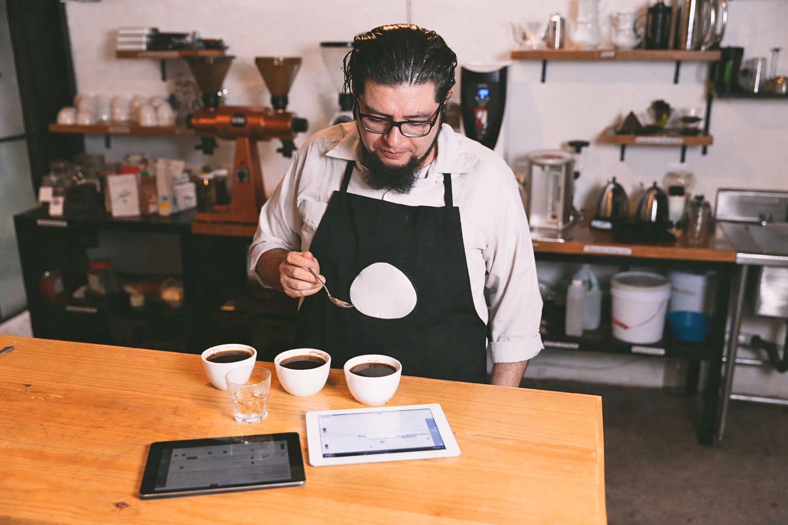 “Coffee professional cupping and evaluating coffee quality as part of sourcing decisions between certified coffee and direct trade.”