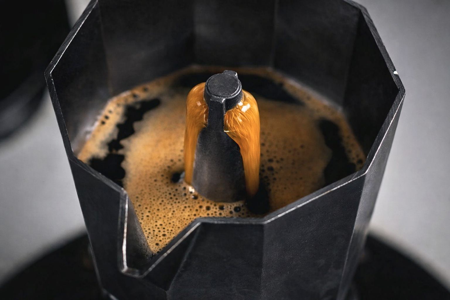 Coffee extracting smoothly from a moka pot with controlled heat to reduce bitterness and improve flavor balance