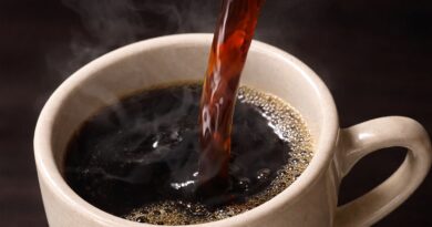Hot black coffee being poured into a ceramic cup.